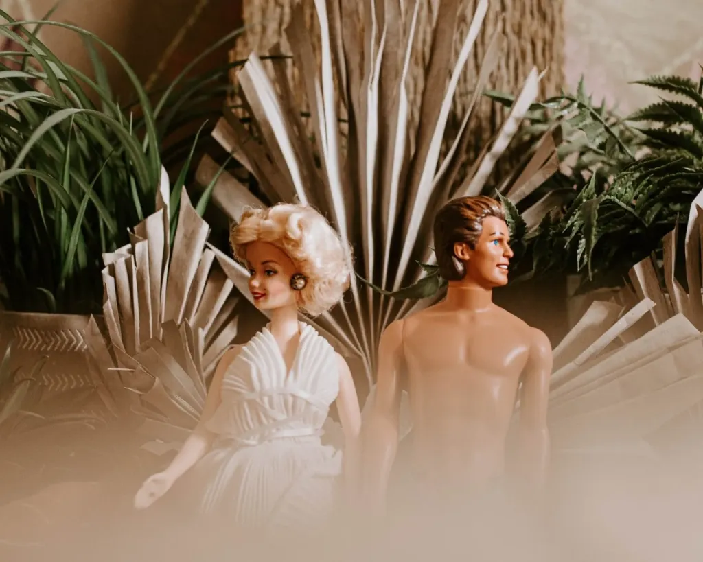 Barbie and Ken doll sitting amongst plants 